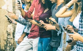 Group of multicultural friends using smartphone outdoors - People hands addicted by mobile smart phone - Technology concept with connected men and women - Shallow depth of field on vintage filter tone
