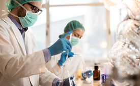 Young scientist working with chemical substances in a laboratory. His colleague is in the background.