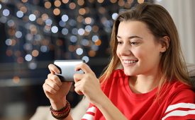 Teen watching media in a smart phone in the night sitting on a couch in the living room at home