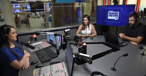 Os âncoras da BandNews FM, Carla Bigatto, Sheila Magalhães e Luiz Megale, no estúdio da emissora em São