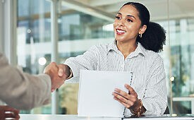 Duas pessoas apertando as mãos em um ambiente corporativo.