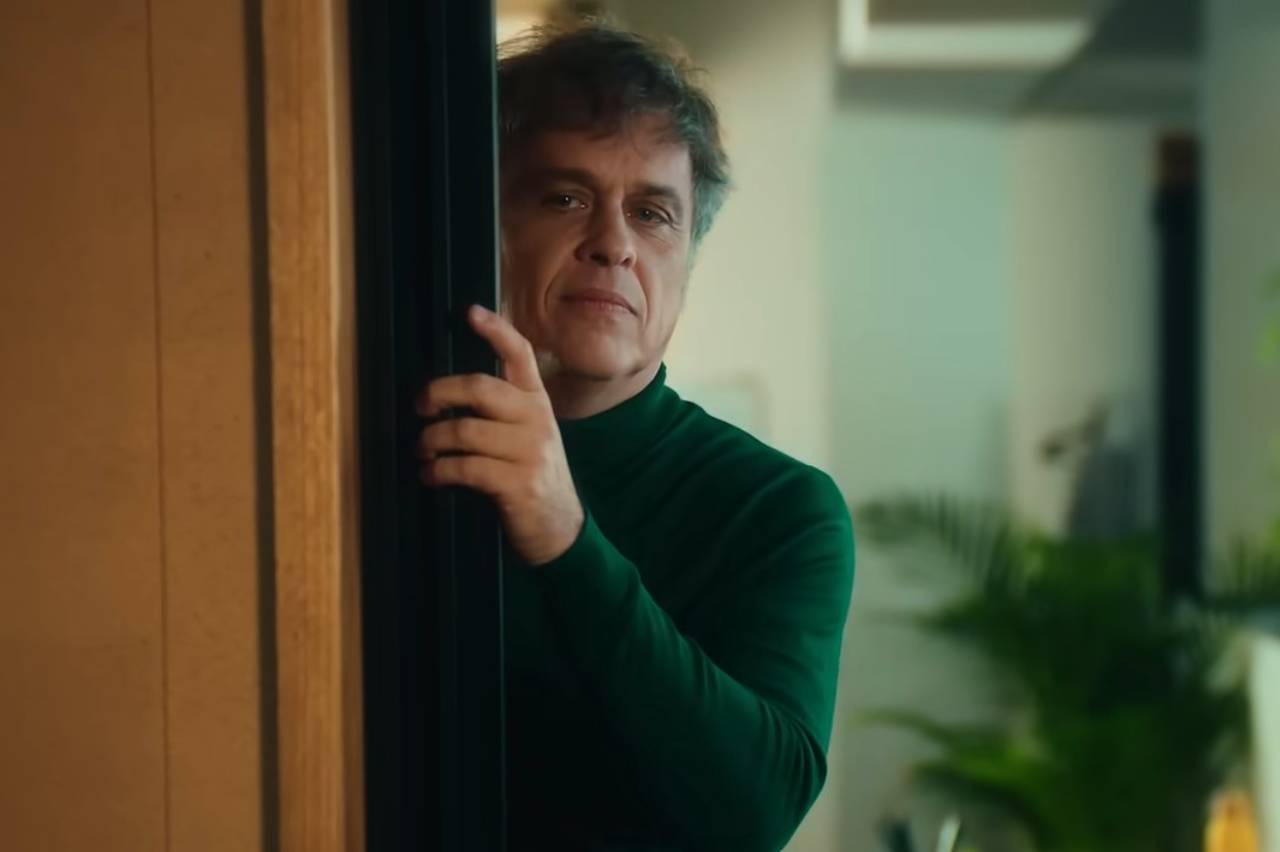 Subway campanha - Retrato de homem com cabelo grisalho e suéter de gola alta verde.