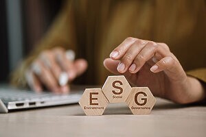 Pessoa posiciona peças ESG de madeira, representando sustentabilidade e governança corporativa.