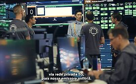 Homens em sala de controle com telas grandes, monitorando transmissão via rede 5G privada.