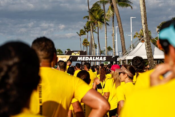 Multidão de corredores com camisas amarelas se aproxima da área de medalhas em evento esportivo.